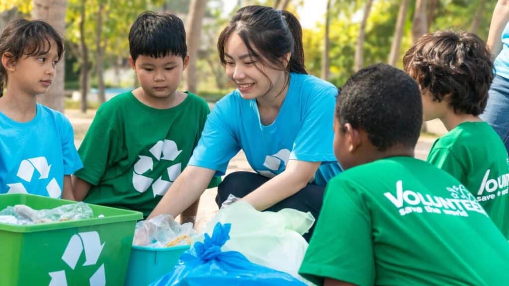 Group of kids school volunteer charity with garbage bags cleaning up on the beach