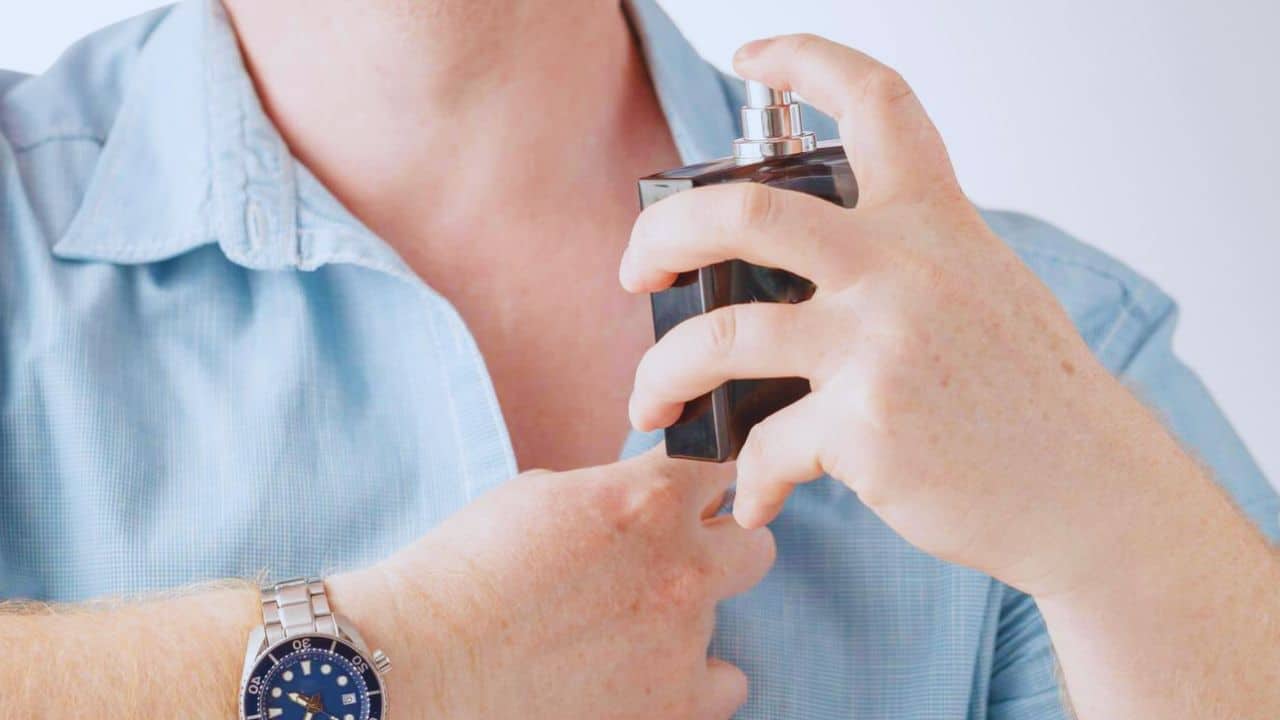 Man applying perfume on his neck on white background