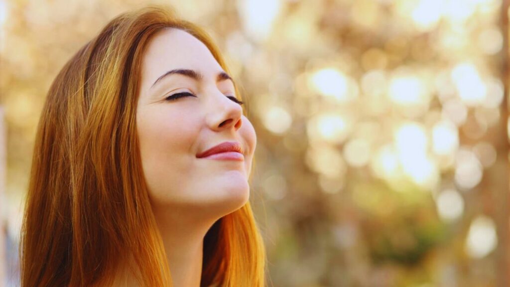 Portrait of a beautiful woman doing breath exercises with an autumn unfocused background