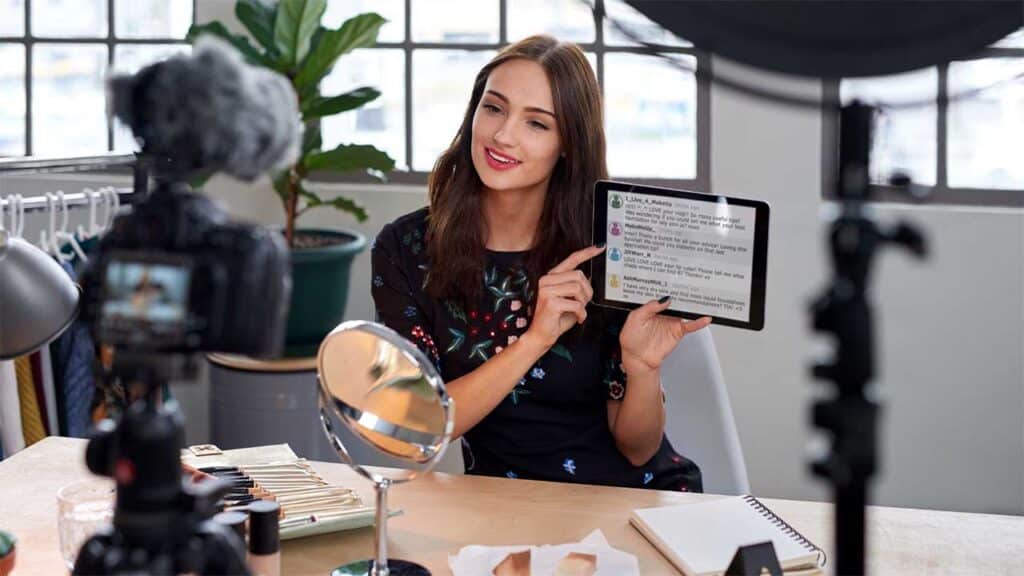 Beauty influencer showcasing makeup tips on a tablet during a live stream.