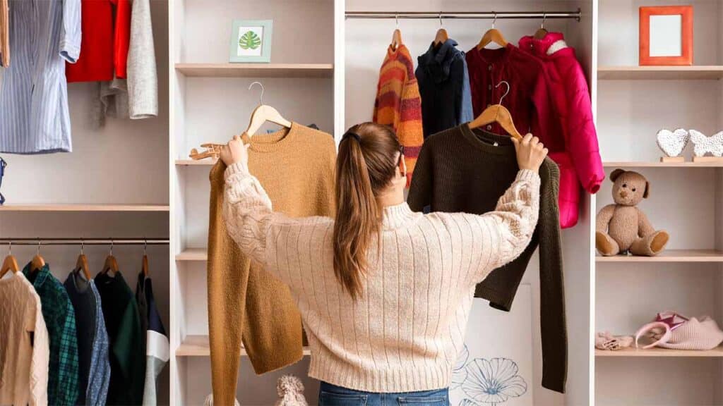 Women choosing between two sweaters in a neatly organized closet