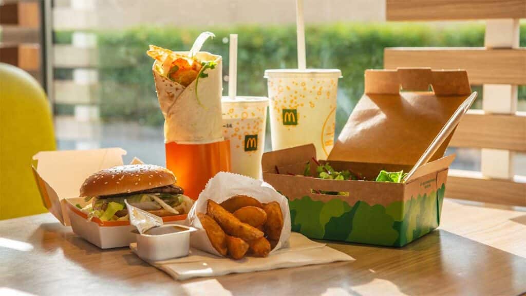 McDonald's meal with a burger, wrap, potato wedges, salad, and drinks.